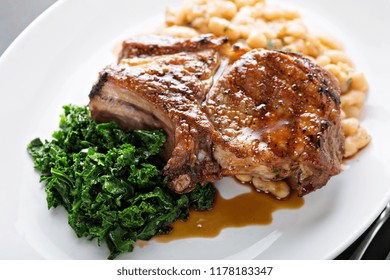 Grilled Pork Chop With Bean Cassoulet, Apple Cider Glaze And Braised Greens