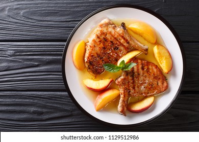 Grilled Pork Chop With Glazed Peaches And Honey Garlic Sauce Close-up On A Plate On A Table. Horizontal Top View From Above
