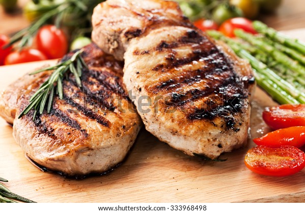 grilled pork\
chop with vegetable on wooden\
board