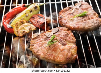 Grilled pork chop and vegetables on the flaming grill. - Shutterstock ID 524191162