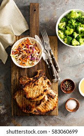 Grilled Pork Chops With Cole Slaw Salad And Steamed Broccoli.