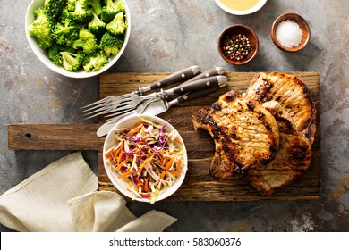 Grilled Pork Chops With Cole Slaw Salad And Steamed Broccoli.