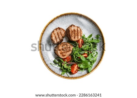 Grilled pork medallions steaks, tenderloin fillet with salad in plate. Isolated on white background
