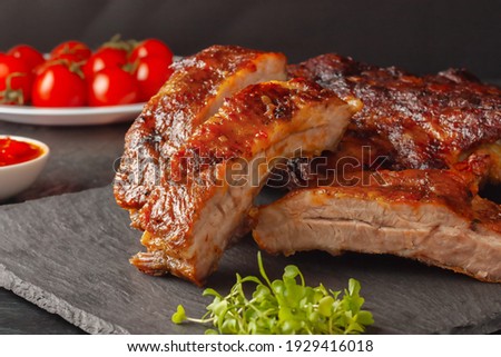 Grilled pork ribs, served on a graphite board with tomatoes