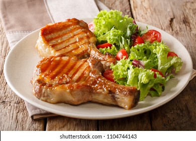 Grilled Pork Steak With A Bone In A Sweet Honey Glaze And A Salad Of Fresh Vegetables Close-up On A Plate On A Table. Horizontal
