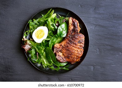 Grilled Pork Steak With Green Salad On Dark Background, Top View.