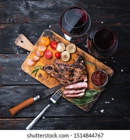 Grilled Pork Steak On A Cutting Board, Delicious Pieces Of Meat, A Glass Of Red Wine. Dinner For Two