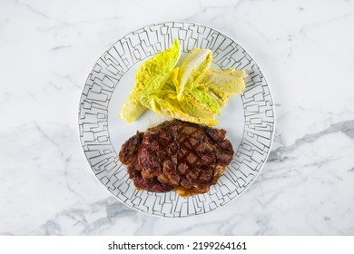 Grilled Pork Steaks With Romaine Lettuce On A White Round Plate. Horizontal Orientation 