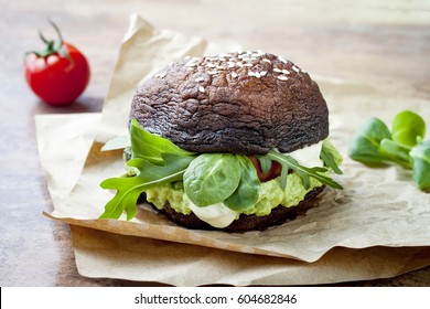 Grilled Portobello Bun Mushroom Burger. Vegan, Gluten Free, Grain Free, Healthy Veggies Hamburger With Guacamole, Fresh Vegetables And Cashew Cheese Sauce.