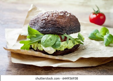 Grilled Portobello Bun Mushroom Burger. Vegan, Gluten Free, Grain Free, Healthy Veggies Hamburger With Guacamole, Fresh Vegetables And Cashew Cheese Sauce.