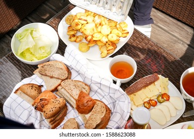 Grilled Potatoes, Salad, Sliced Bread, Cup Of Tea, And Cheese Slices On Plastic Table Outside - Grilling Concept