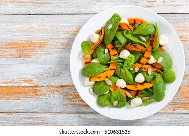 Grilled Pumpkin, Mini Mozzarella, Baby Spinach And Pumpkin Seeds Healthy Autumn Salad On White Platter, On Peeling Paint Wooden Table, View From Above