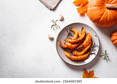 Grilled pumpkin slices with garlic and herbs on white background, copy space. Oven baked pumpkin, seasonal autumn side dish or vegan meal.