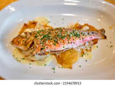 Grilled Red Mullet Serverd Over Baked Potatoes And Dressing With Chives.
