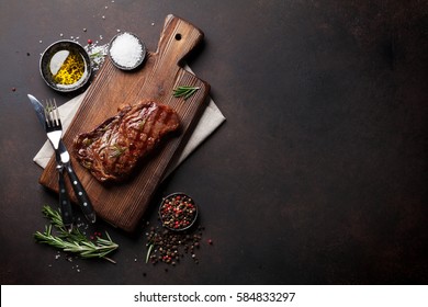 Grilled ribeye beef steak, herbs and spices. Top view with copy space for your text - Shutterstock ID 584833297
