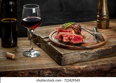 Grilled ribeye beef steak with red wine, herbs and spices on wooden table