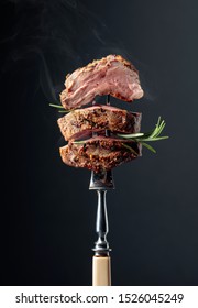 Grilled ribeye beef steak with rosemary on a black background.  Beef steak on a fork. - Shutterstock ID 1526045249