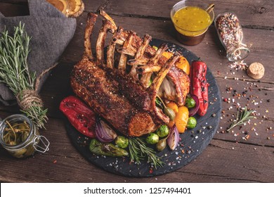 Grilled roasted rack of lamb veal chops with vegetables, on a wooden surface