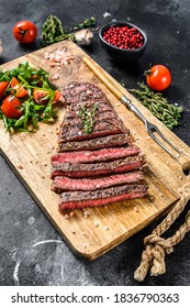 Grilled rump steak with spices on a chopping Board. Barbecue beef. Black background. Top view. - Shutterstock ID 1836790363
