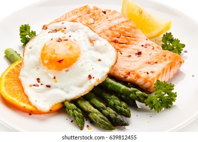 Grilled salmon with asparagus and fried egg on white background 
