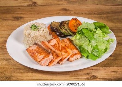 Grilled Salmon Fillet With Brown Rice, Green Salad And Grilled Vegetables Served In A Restaurant