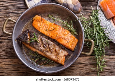 Grilled salmon fillets and herb decoration in old roasted pan. 