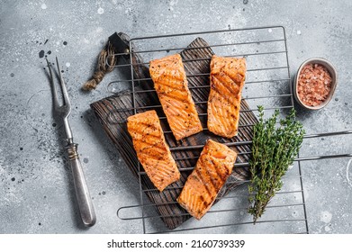 Grilled salmon fillets steaks with salt pepper and herb on grill. Gray background. Top view.