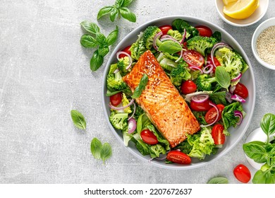 Grilled salmon fish fillet and fresh green leafy vegetable salad with tomatoes, red onion and broccoli. Healthy food. Ketogenic lunch. Top view - Powered by Shutterstock