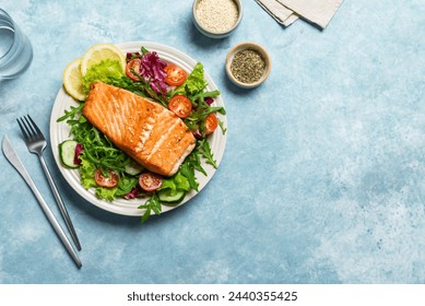 Grilled salmon fish fillet and fresh vegetable salad. Healthy keto food - green salad and roasted salmon on blue background, copy space. Barbecue meal. - Powered by Shutterstock