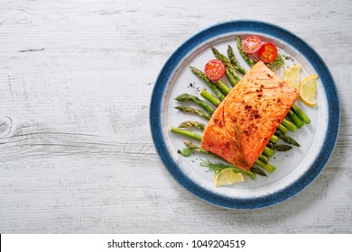 Grilled salmon garnished with green asparagus and tomatoes.Top view