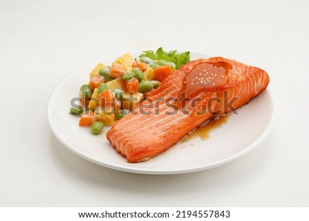 Grilled salmon with sesame seed and teriyaki sauce and sweet omelette or japanese salad in a plate on white background.