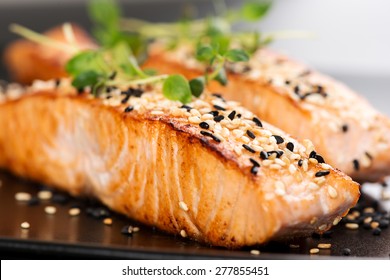 Grilled salmon, sesame seeds  and marjoram on a black plate. Studio shot - Shutterstock ID 277855451