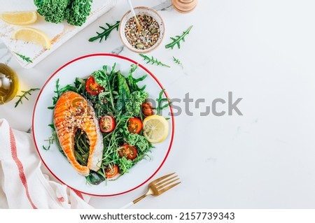 Grilled Salmon steak and fresh vegetable salad with a lemon over white marble background. Healty food concept. Top view with copy space