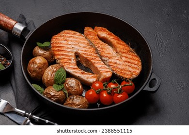 Grilled salmon steaks and potatoes sizzling in a frying pan, a mouthwatering delight - Powered by Shutterstock