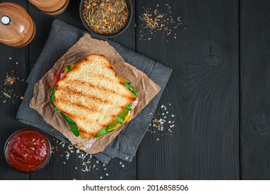 Grilled Sandwich With Vegetables, Ham And Cheese On A Black Background. Top View. Fast Food.