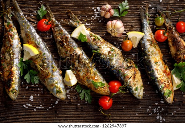 Grilled sardines with addition of fresh herbs, lemon and spices on a ...