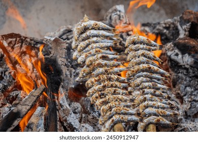 Grilled sardines, known as Espetos, are a traditional Spanish cuisine in Malaga, Spain. The fresh fish is cooked on skewers over an open wood fire barbeque pit shaped as a boat. Hot Málaga sardines. - Powered by Shutterstock