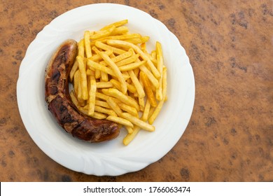 Grilled Sausage, German Bratwurst, And French Fries On A Plate In A Fast Food Restaurant, Tasty But Unhealthy Eating With Trans Fat And Saturated Fatty Acids, Copy Space, High Angle View From Above