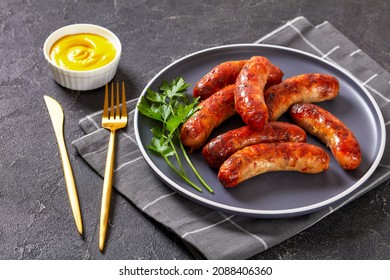 grilled sausages, bangers on a plate on a concrete table, horizontal view from above