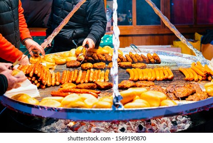 Grilled Sausages At Christmas Market At Town Hall In Winter Berlin, Germany. BBQ Meat Food At Advent Fair And Stalls With Crafts Items On The Bazaar.