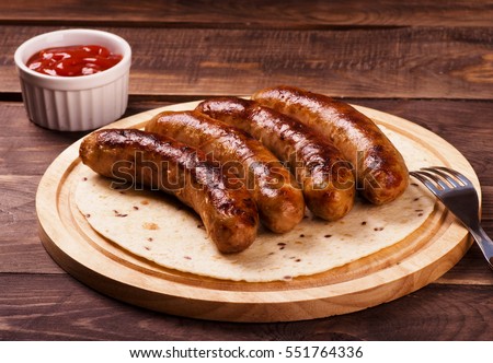 Grilled sausages with sauce ketchup on a wooden table