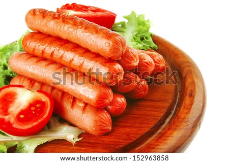 grilled sausages served on wooden plate with vegetables