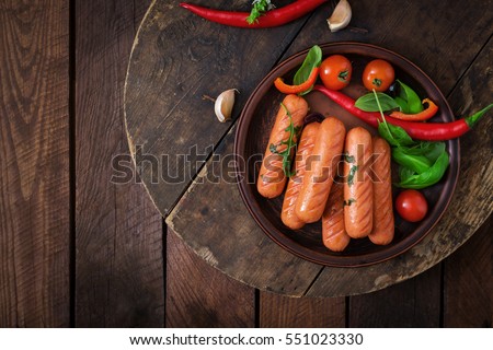 Grilled sausages and vegetables on a wooden background in rustic style. Top view. Flat lay