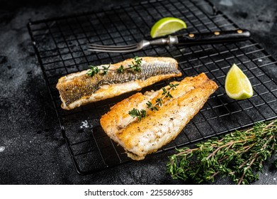 Grilled sea bass fillet with lime and thyme. Black background. Top view.