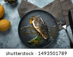 Grilled seabass with eggplant and lime. Horizontal top view, top shot. Copy space, gray concrete marble background, soft light. Food Fashion Photo.