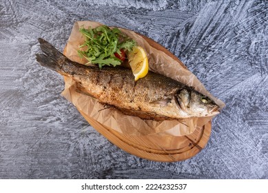 Grilled seabass on the wooden board. Baked sea Bass fish. Top view