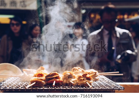 grilled seafood scallop and sea urchin eggs skewer with smoke, japanese street food at Tsukiji Fish Market, Japan. selective focus and film style.