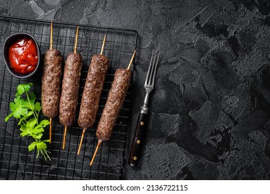 Grilled shish kebab, arabic kofta kofte kebab from mince lamb and beef meat on Skewer. Black background. Top view. Copy space.