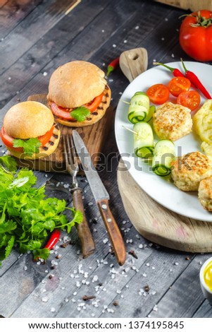 Grilled shish kebab meat steak cutlets fried on a wooden vintage old rustic board, on a plate, chili, burgers with tomatoes and cucumbers, sauce, herbs on the table top, side, bottom, fork knife