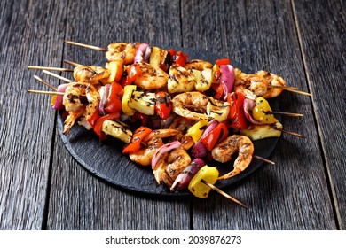 Grilled Shrimp Kabobs with charred red onion, sweet pepper and pineapple on a black stone platter